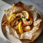 Close-up of cooked shrimp scampi en papillote garnished with lemon slices and fresh parsley, served in its parchment paper pouch.